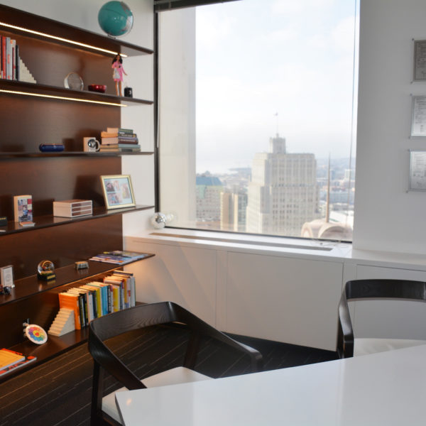 Gorgeous minimal office with designed chairs and custom lit shelving.